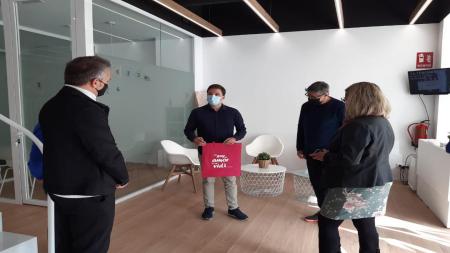 Los representantes de Mazuelas muestran la bolsa rosa que pondrán a la venta próximamente, cuyos beneficios serán para la AECC.