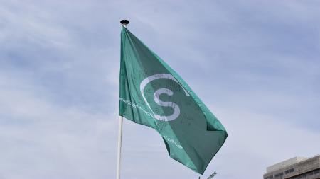 Bandera verde de la lucha contra el cáncer firmada e izada en el centro de Madrid.