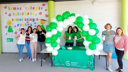 Profesoras del colegio Isabel la Católica posan con la huchas, junto a la mesa de Cuestación adornada con globos instalada en el ce.